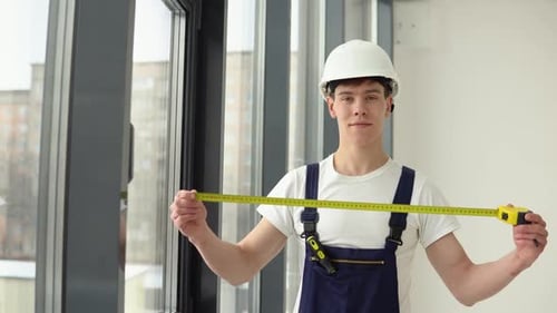 O instalador de janelas mede as dimensões da moldura da janela com uma fita métrica