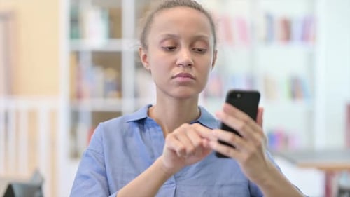 Surprised Young Woman Using Smartphone Indoors