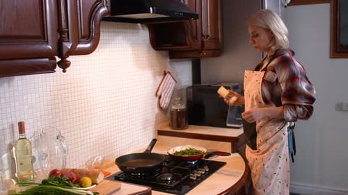 Side View of Gorgeous Caucasian Woman Cooking in Kitchen at Home Answering Phone Call