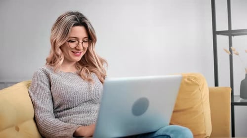Woman Using Laptop Computer Sitting on Couch Indoors