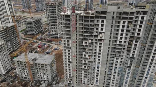 Flight Over The Construction Site. High Rise Buildings Under Construction And Construction Cranes
