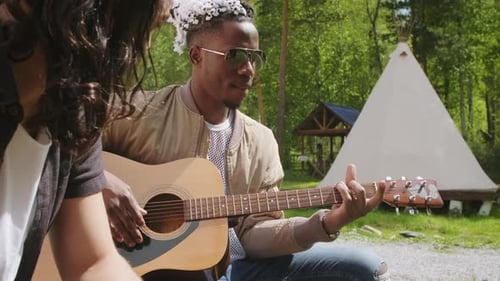Multi-Ethnic Friends Playing Guitar In Park