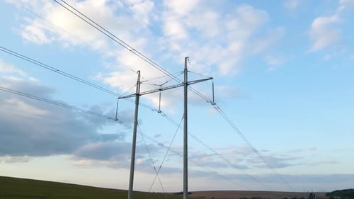 Dark Silhouette of High Voltage Tower with Electric Power Lines at Sunset
