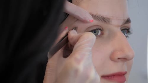 Woman Getting Eyebrows Groomed with Tweezers