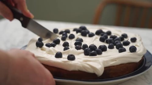 Cutting into Blueberry Cake with White Frosting