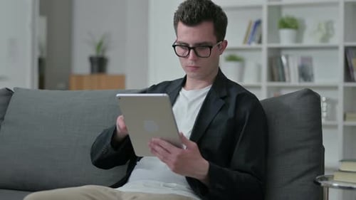 Young Adult Using Tablet on Couch Indoors