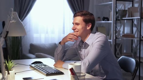 Young Man Typing at Computer in Home Office