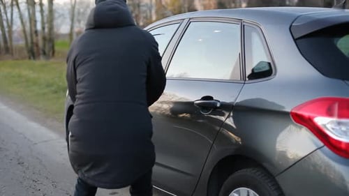 Thief in mask trying to steal a car