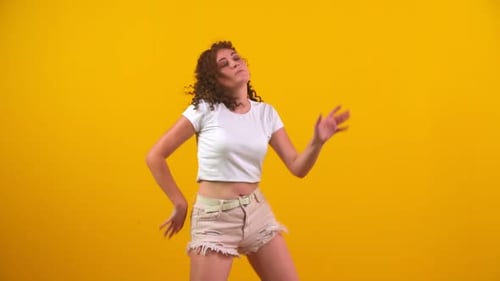 Woman Dances Energetically in Studio with Yellow Background