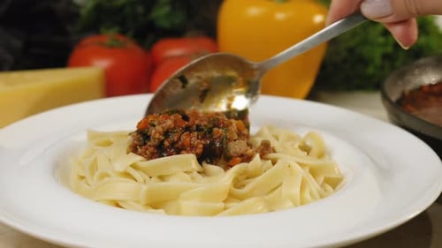 Preparing pasta with meat sauce on a plate