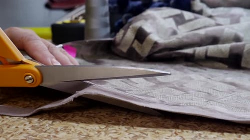 Woman Cuts Patterned Fabric with Scissors