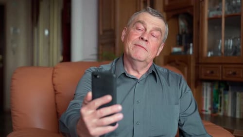 Mature Man Talking on Smartphone Video Call Indoors