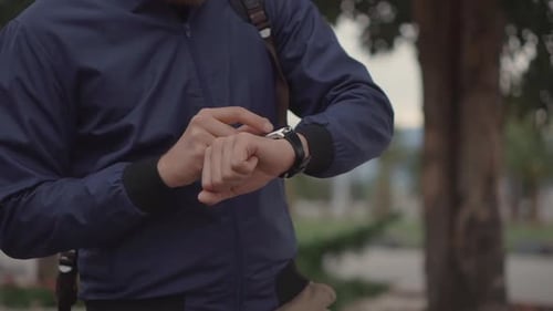 Man Uses Smart Watch Device in Park