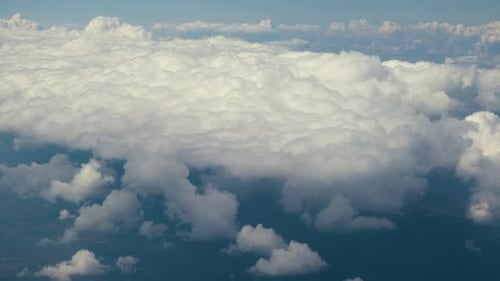 Aerial View From Airplane Window of White Puffy Clouds on Bright Sunny Day