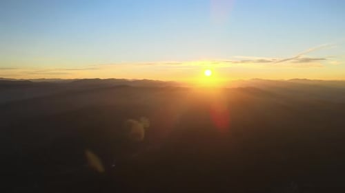 Luftaufnahme der dunklen Berghügel mit hellen Sonnenstrahlen der untergehenden Sonne bei Sonnenuntergang