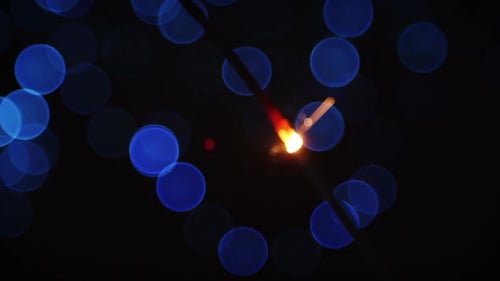 Festive Golden Sparkler with Blue Bokeh Lights