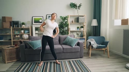 Woman Stretching and Exercising in Bright Living Room