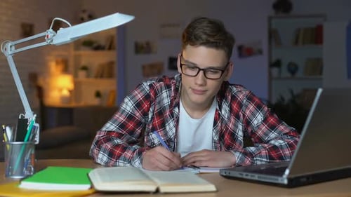 Fleißiger Jugendstudent mit Brille erledigt die Hausaufgaben und schaut direkt in die Kamera