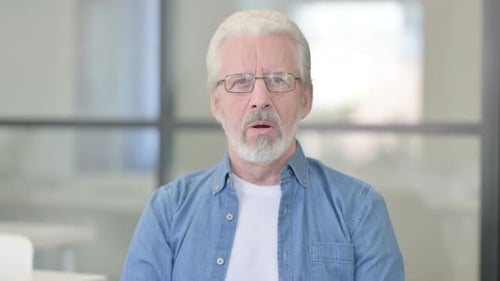 Adult Grey Haired Man with Glasses Stares Directly