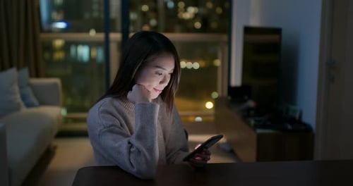 Woman Using Mobile Phone at Home at Night