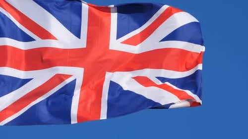Union Jack Flag Waving Proudly Against Blue Sky