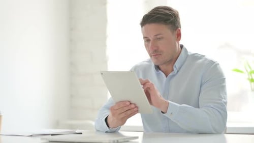 Man using Tablet while Sitting in Office
