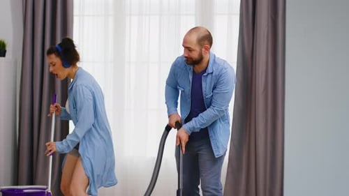 Playful Couple Cleaning and Dancing Together at Home