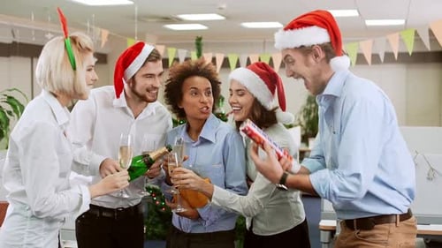 Colegas felizes levantando seus óculos para uma festa de brinde no escritório. Câmera lenta