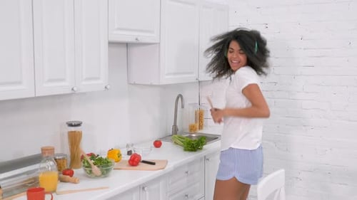 Energetic Woman Dancing in Kitchen While Making Salad