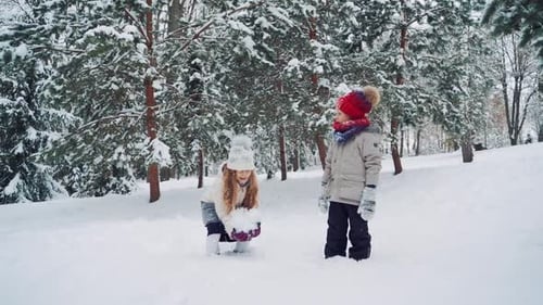 Ein amüsantes Mädchen mit einem großen Schneeklumpen in den Händen