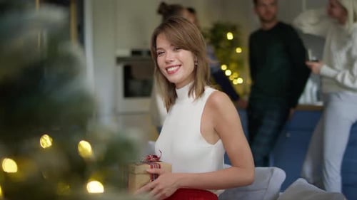 Woman with Christmas Gift Surrounded by Friends at Home
