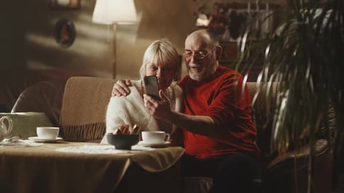 Senior Couple Using Smartphone Together at Home