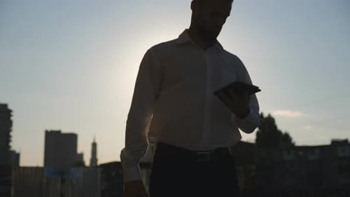 Young Entrepreneur with Briefcase Uses Smartphone Walking at Urban Street