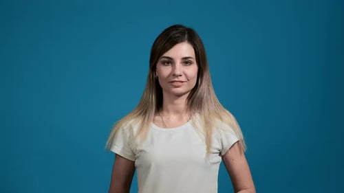 Hermosa mujer con cabello rubio en camiseta blanca sobre azul