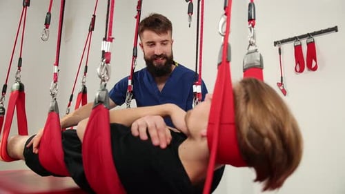 Man Assists Person Suspended in Straps