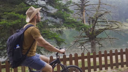 Man Cycling Along Lake in Natural Setting