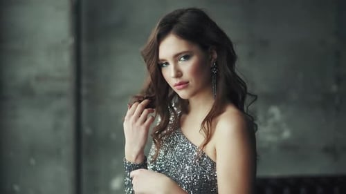 Girl in Evening Dress Touches Her Hair and Playfully Looks Into the Camera
