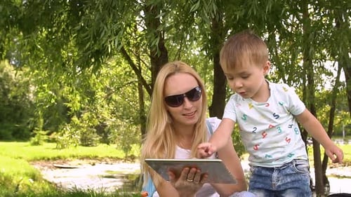 Mother and Child Use Tablet in Park Setting