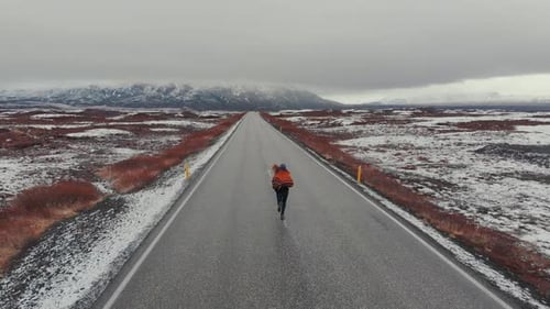 Aerial view of woman running in road in terrain snowy