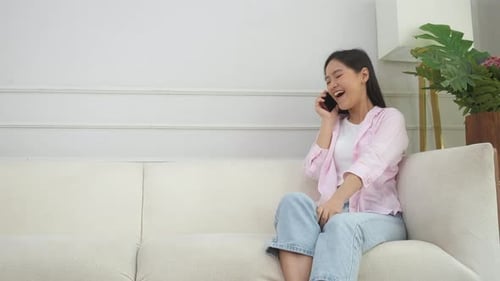 Smiling Woman Talking on Smartphone on Couch