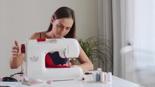 Woman Sews Red Fabric With Sewing Machine