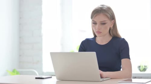 Surprised Woman Working on Laptop in Bright Office