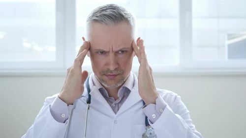 Stressed Doctor with Headache in Clinic