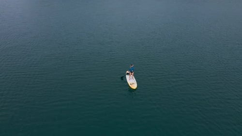 Woman Paddle Boarding on a Calm Lake