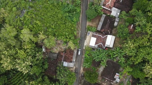 Aerial view of a car riding on the small road through village on the countryside in Indonesia
