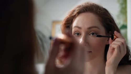 Caucasian woman applying eyelash in the mirror reflection. Shot with RED helium camera in 4K.