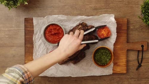 Anonymous person serving grilled tomatoes near Salisbury steaks with sauces