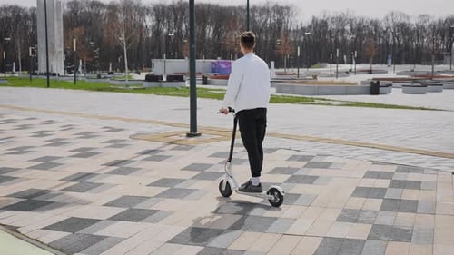 Un jeune homme séduisant conduit un scooter électrique
