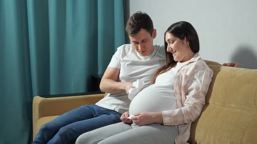 Loving Couple with Baby Shoe on Couch
