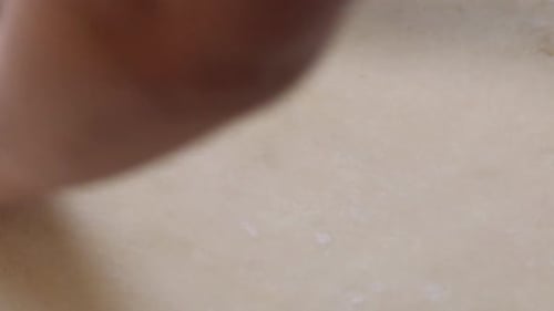 A Woman Rolls Out The Dough For Cinnabons With A Rolling Pin. On A White Tabletop. Close Up Shot